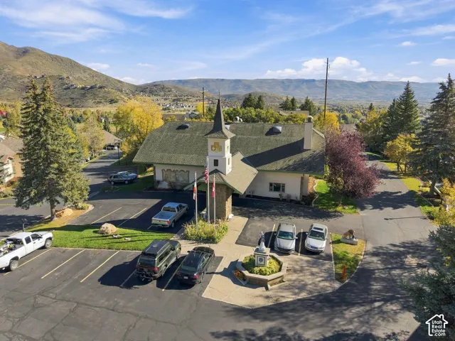 Exterior featuring a distinctive architectural tower, asphalt parking lot, stone-veneer accents, and a mountain backdrop