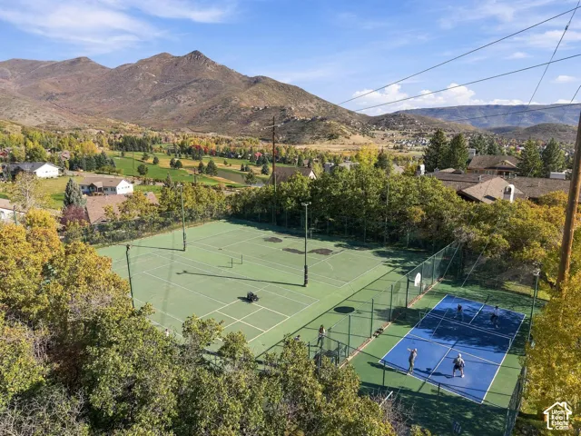 Tennis and pickleball courts featuring perimeter fencing, surrounded by mature trees and mountain scenery