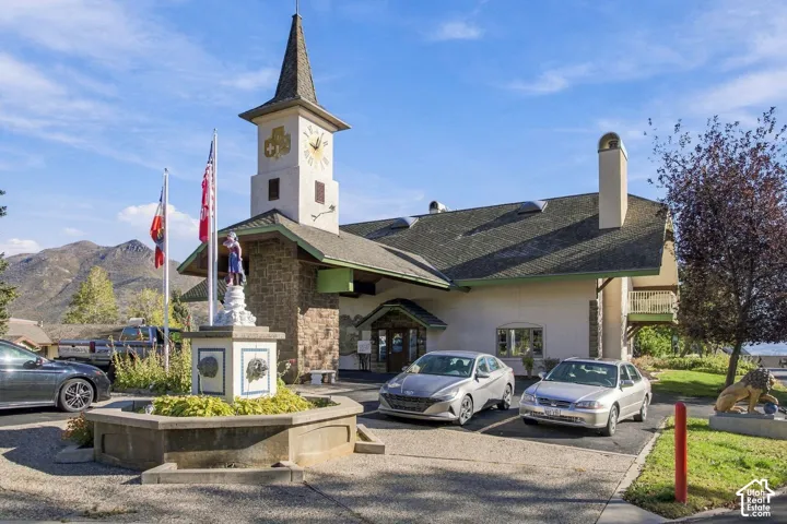 Stucco exterior featuring a prominent clock tower, stone masonry accents, a multi-pitched roofline with skylights, and a decorative pedestal fountain