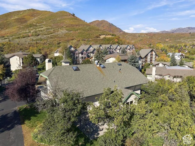 Aerial perspective featuring a multi-level structure with a gabled roof, integrated skylights, and mountain terrain backdrop