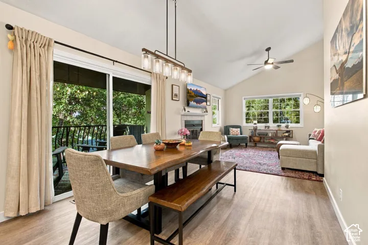 Vaulted ceiling, wood-finish flooring, linear five-light pendant fixture, fireplace with mantel, and sliding glass doors