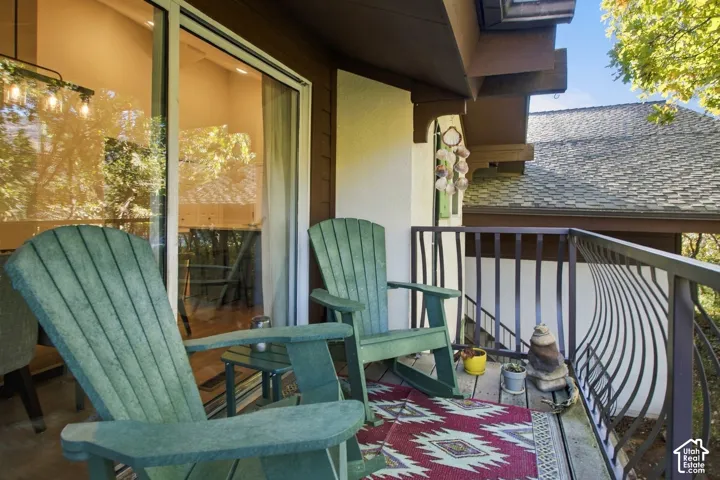 Exterior balcony featuring horizontal wood siding, a metal railing with a curved spindle pattern, and large glass sliding doors