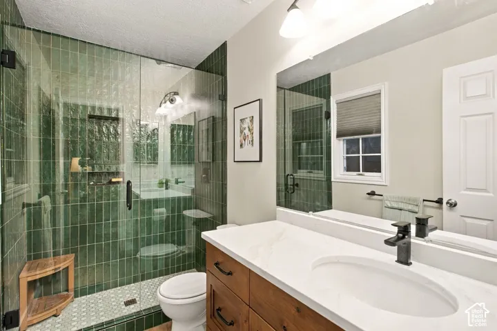Walk-in shower featuring green vertical tiling, glass enclosure, and stone-patterned floor tiling