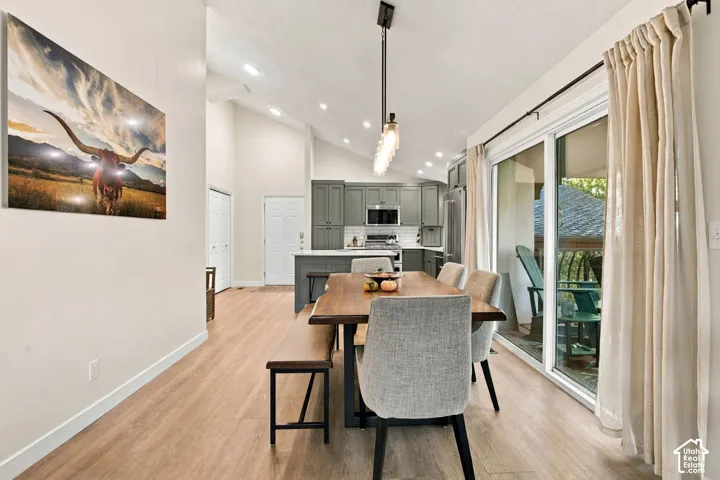 Vaulted ceilings with recessed lighting, wood-finish flooring, sliding glass door, and cabinetry featuring a built-in microwave and stainless steel appliances