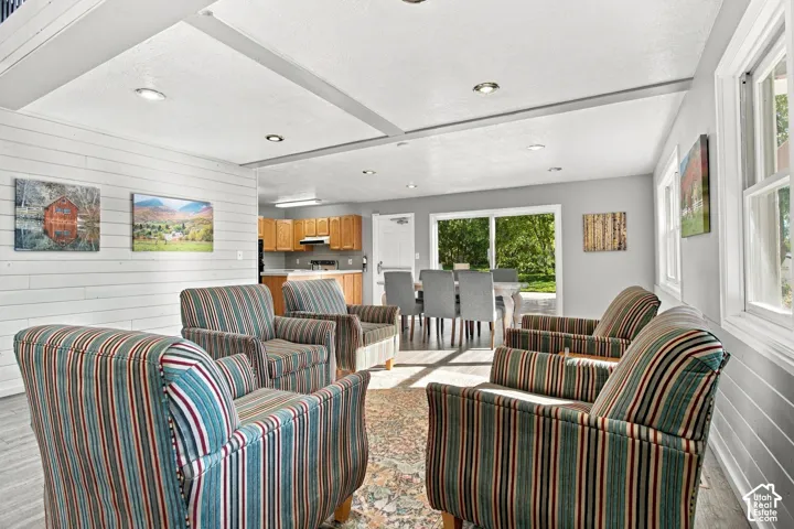 Horizontal plank wall paneling, recessed ceiling lighting, wood-finish flooring, and a sliding glass door providing external access