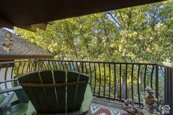 Covered deck featuring metal railing and mature tree canopy