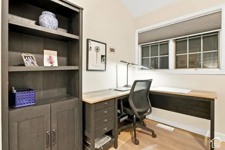 Built-in floor-to-ceiling wood-finish shelving unit, multi-pane window with custom pleated shade, and vaulted ceiling