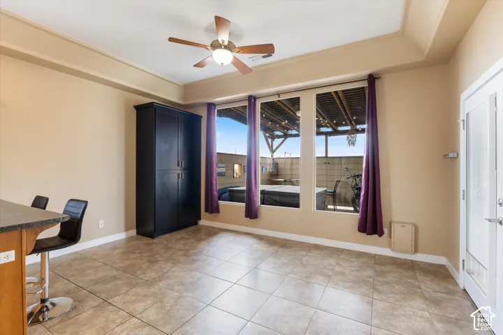 Tray ceiling with recessed lighting, tile flooring, built-in cabinetry, and large windows with natural light