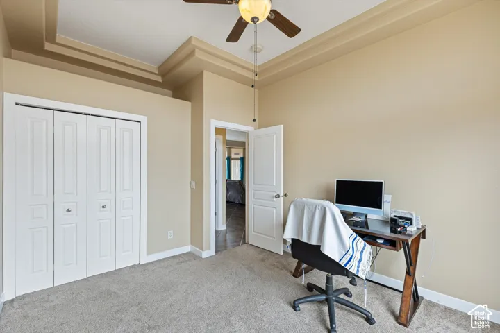Tray ceiling, carpeted flooring, bi-fold closet doors, and a ceiling fan with integrated lighting