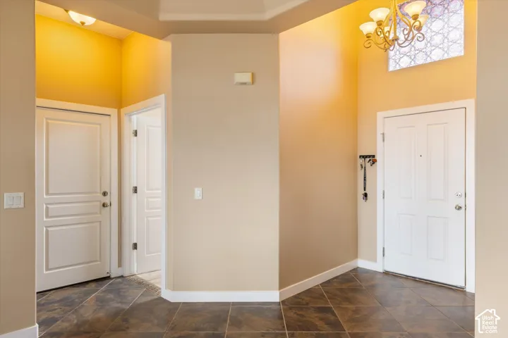 Foyer featuring high ceilings, multi-pane transom window, multi-bulb chandelier, and tiled flooring
