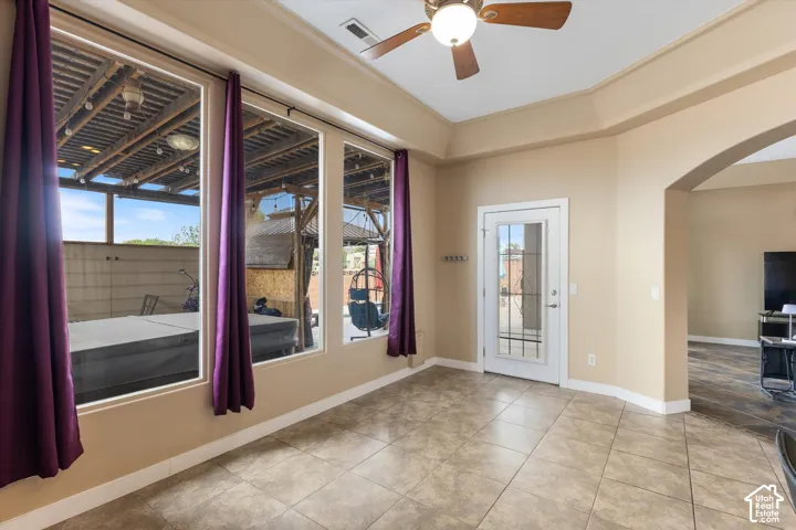 Tiled flooring, high tray ceiling with integrated ceiling fan, and large windows with natural light exposure