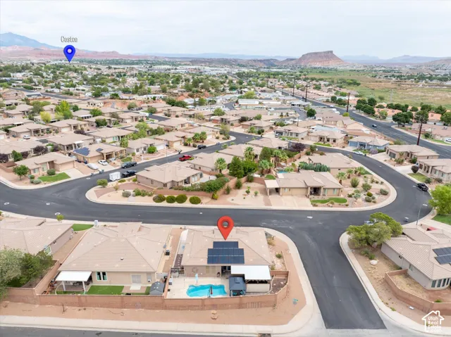 Aerial perspective featuring a property with integrated rooftop solar panels, a private swimming pool, and a perimeter wall