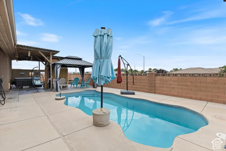 Backyard featuring an in-ground swimming pool, concrete decking, covered patio area, and masonry perimeter wall