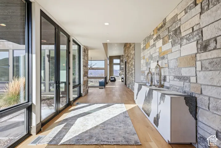 Hallway featuring floor-to-ceiling windows, wood-finish flooring, recessed lighting, and an exposed stone accent wall