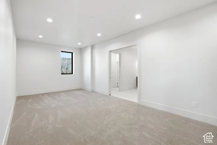 Spacious room featuring neutral carpet flooring, recessed lighting, and a black-framed window