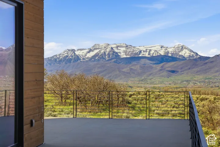 Expansive outdoor deck featuring a dark gray surface, metal cable railing, and a wood-paneled exterior wall