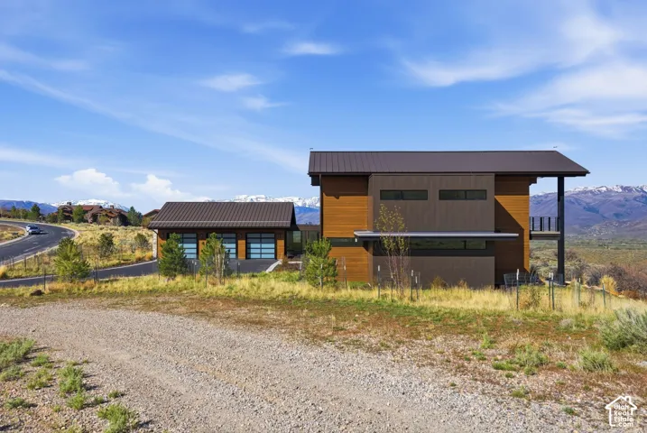 Contemporary architecture featuring warm wood and dark siding, a metal roof, and a private balcony