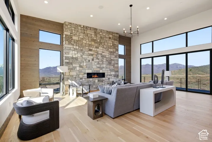 Spacious living area featuring a floor-to-ceiling stone fireplace with a horizontal gas insert, light wood-finish flooring, and high ceilings with recessed lighting