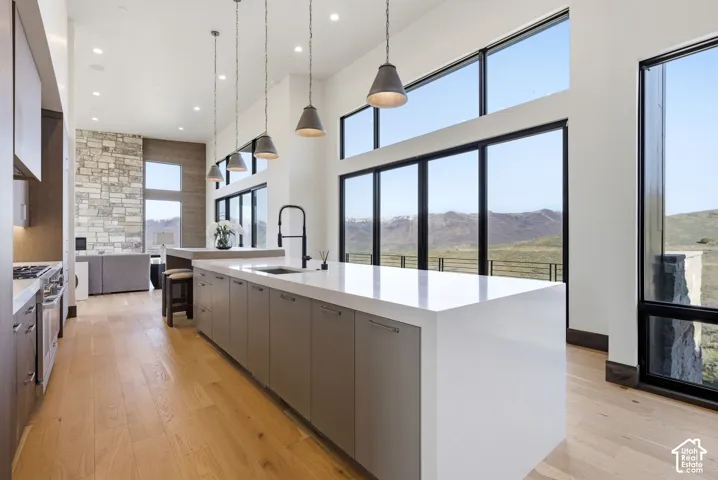 Open-concept kitchen featuring a large central island with white countertop, integrated sink, and pendant lighting