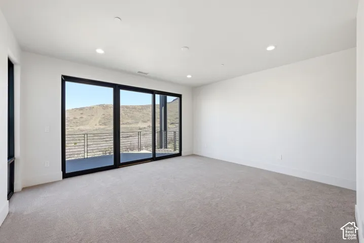 Expansive room featuring large sliding glass doors, a side window, and recessed ceiling lighting
