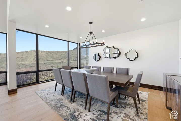 Spacious dining area featuring expansive windows, recessed lighting, light wood-finish flooring, and a contemporary chandelier