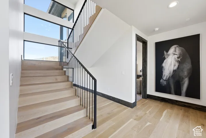 Modern staircase featuring light wood-finish treads and black metal railings