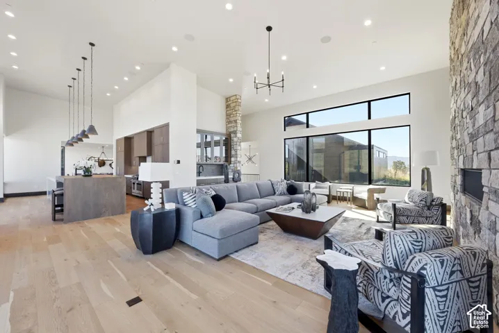 Open-concept living area with high ceilings, light wood-finish flooring, and a stone-clad fireplace