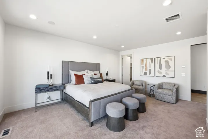 Carpeted bedroom featuring recessed lighting, a built-in ceiling speaker, and an open doorway revealing a closet space