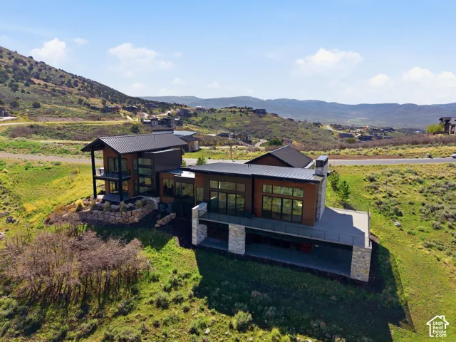 Contemporary multi-level residence featuring expansive window walls, a dark metal roof, and wood-finish siding