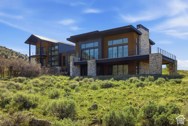Modern architectural residence featuring multiple levels, expansive window walls, natural wood siding, and stone accents