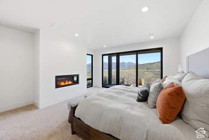 Spacious room featuring broad windows with mountain scenery, a built-in linear fireplace, recessed lighting, and light-toned carpeting