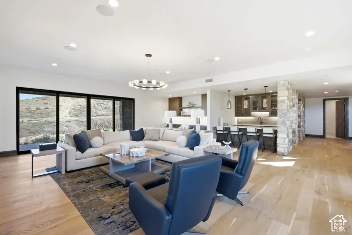 Expansive living area featuring light wood-finish flooring, recessed lighting, and a modern chandelier