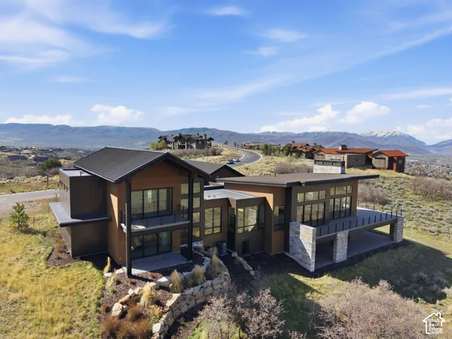 Modern architectural design featuring expansive windows, a metal roof, and a stone facade