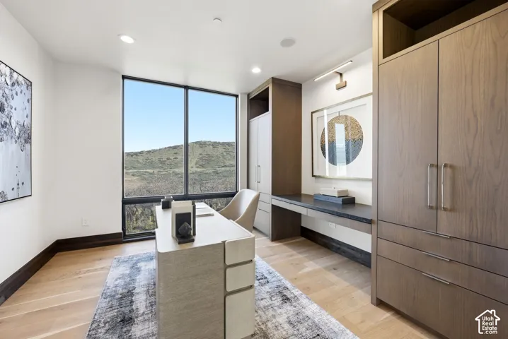 Room featuring light wood-finish flooring, a large picture window, and recessed ceiling lighting