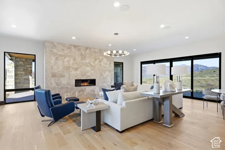 Spacious living area featuring a large format stone-clad fireplace with a linear firebox, light wood-finish flooring, recessed lighting, and expansive sliding glass doors