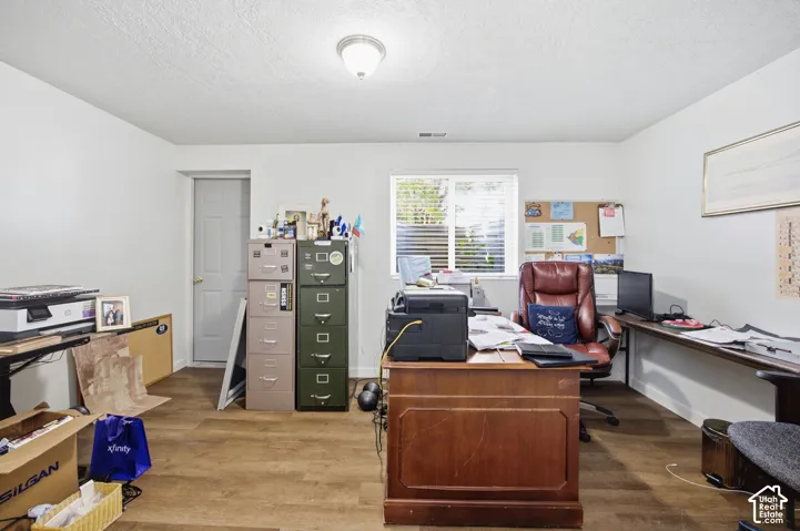 Interior room featuring wood-finish flooring, a single window, a built-in wall-mounted desk, and a flush-mount ceiling light fixture