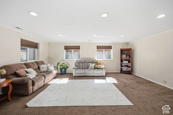 Spacious interior featuring recessed lighting, carpeting, three windows with roller shades, and neutral wall color