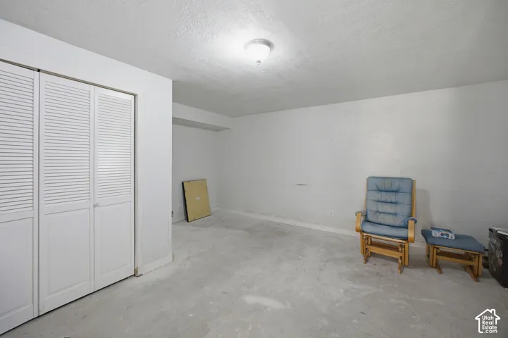 Room featuring white walls, a flush-mount ceiling light fixture, and floor-to-ceiling louvered double closet doors