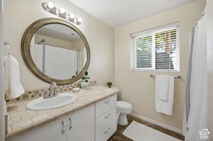 Bathroom vanity featuring a tile countertop, integrated oval sink, white cabinetry with metallic hardware, oval mirror, and a multi-bulb light fixture
