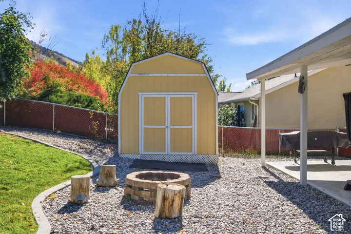 Backyard featuring a shed with a gambrel roof, a stone-block fire pit, gravel ground cover, and a concrete patio