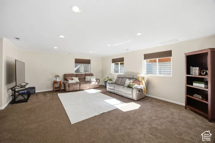 Open-concept room featuring wall-to-wall carpeting, recessed lighting, and multiple windows with integrated shades