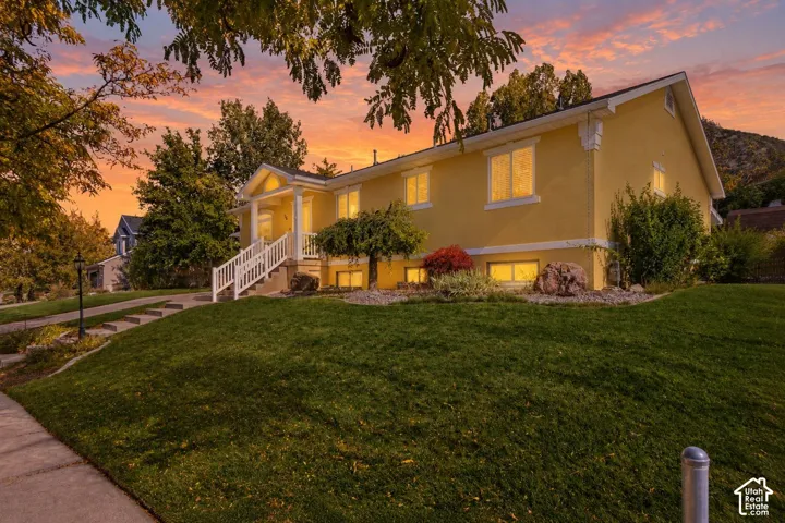 Exterior featuring stucco siding, gabled roofline, covered front entryway with stairs, and manicured landscaping