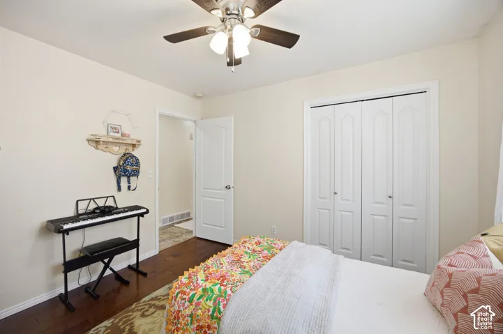 Room featuring dark wood-finish flooring, white paneled interior doors, a double-door closet, and a multi-light ceiling fan