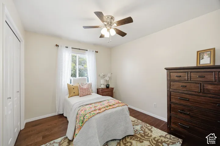 Room featuring dark wood-finish flooring, a ceiling fan with integrated lighting, and a double-door closet