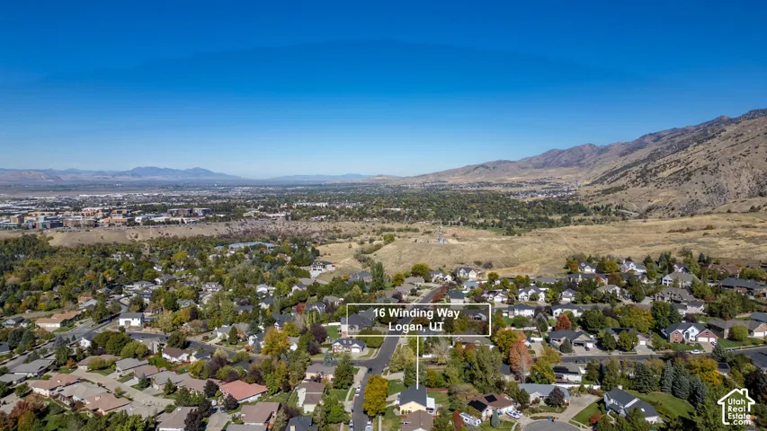 Aerial perspective showcasing a residential property situated against a prominent mountain backdrop with extensive terrain