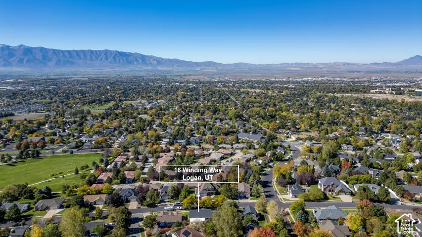 Aerial perspective featuring mature trees, expansive neighborhood grounds, and a prominent mountain range backdrop