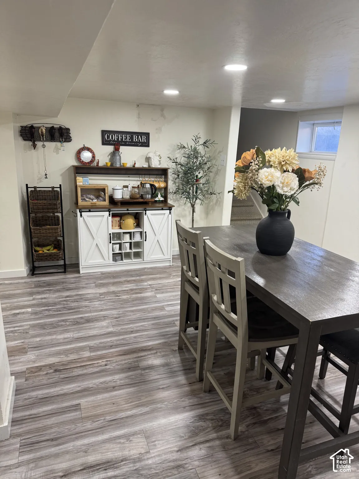 Wood-finish flooring, white built-in cabinetry featuring barn-style doors and an integrated wine rack, and recessed ceiling lighting