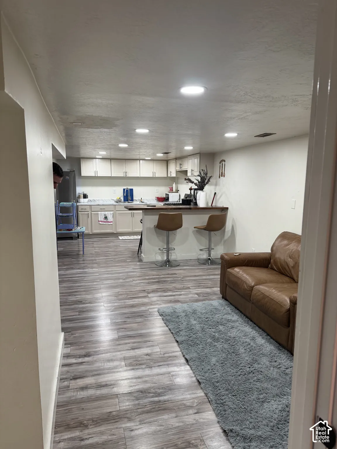 Kitchen in basement featuring wood-finish flooring, white cabinetry, a countertop peninsula, and recessed ceiling lighting