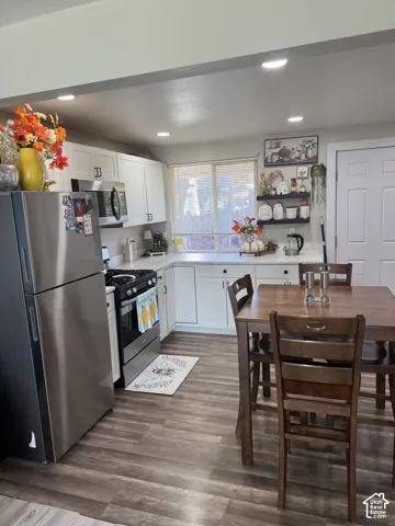 Kitchen featuring white cabinetry, stainless steel appliances, wood-finish flooring, recessed lighting, and a window with blinds