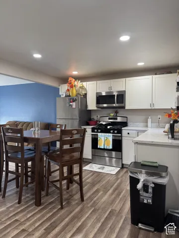 Kitchen featuring white shaker-style cabinetry, wood-finish flooring, recessed lighting, and stainless steel appliances